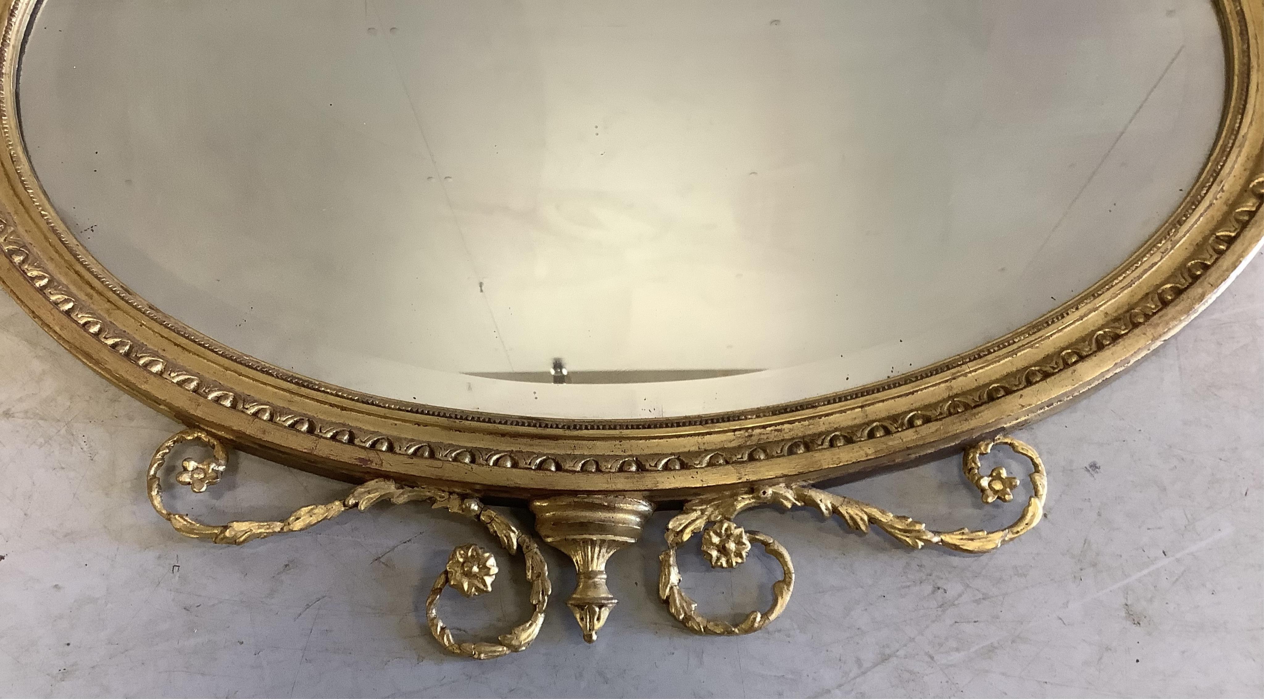 An Edwardian Sheraton Revival oval giltwood and composition wall mirror, width 86cm, height 90cm. Condition - fair